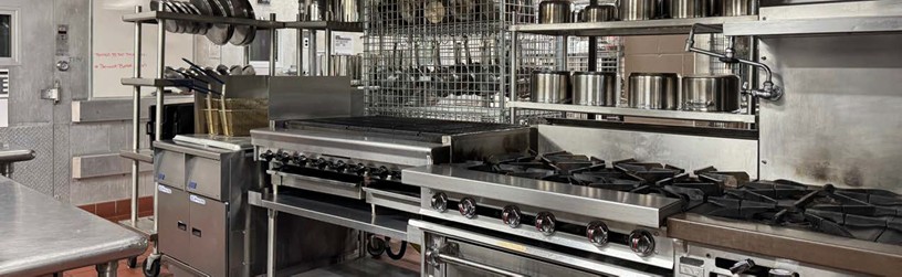 Photo of the Culinary Department kitchen featuring several cooking surfaces with pots and utensils stored neatly above.