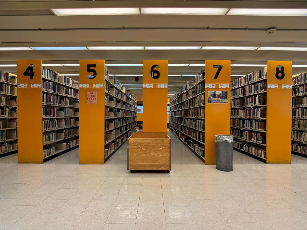 Photo of a library floor with orange numbered book stacks.