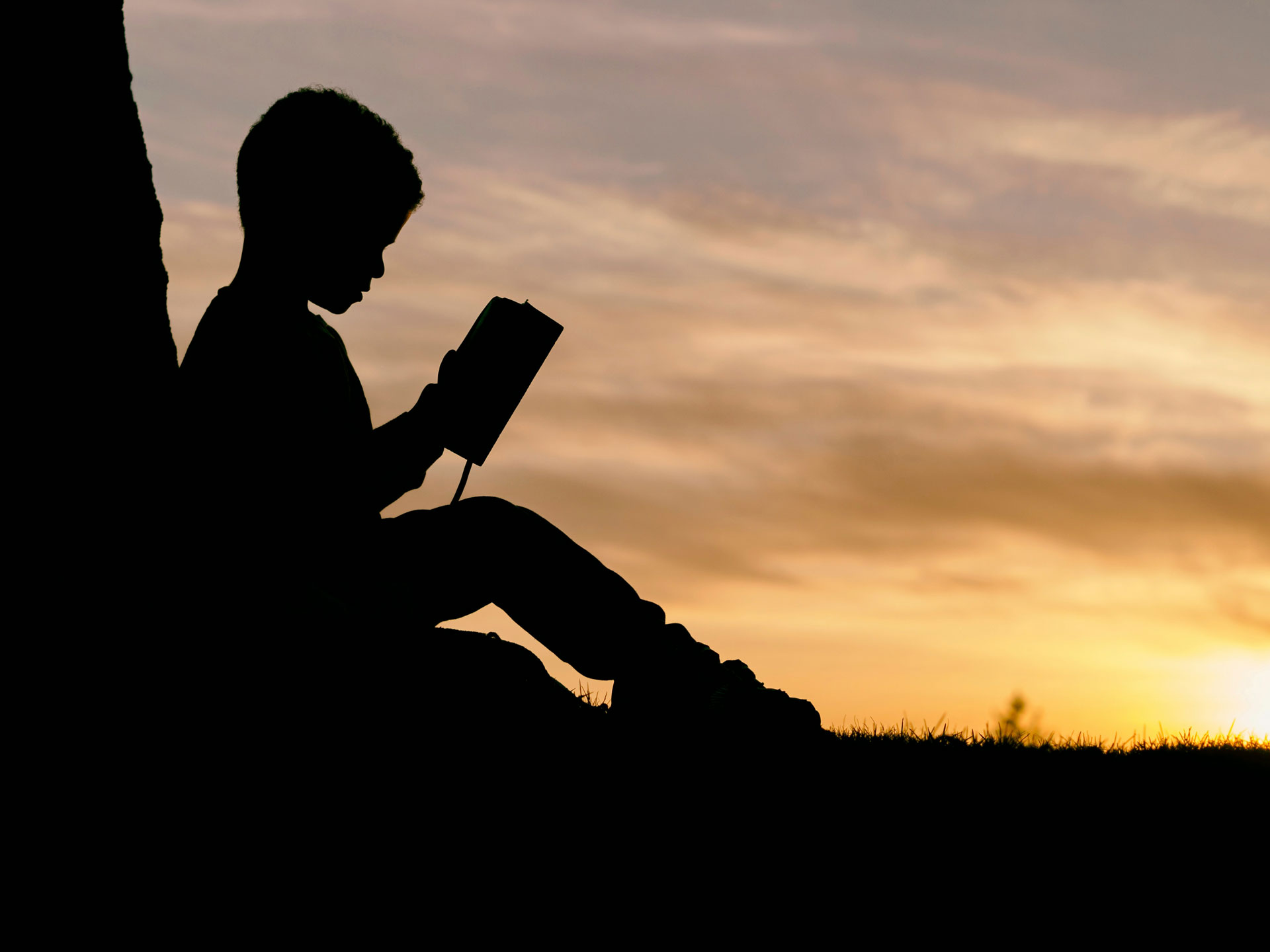 Silhouette of a child reading a book